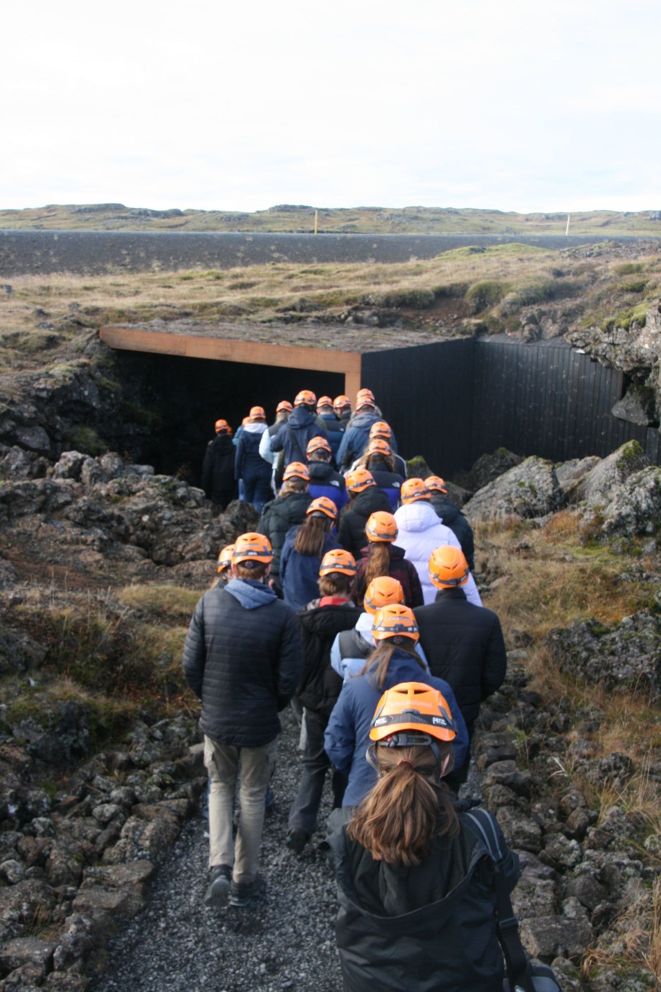 a group of students wearing hard hats exploring inside an Icelandic cave