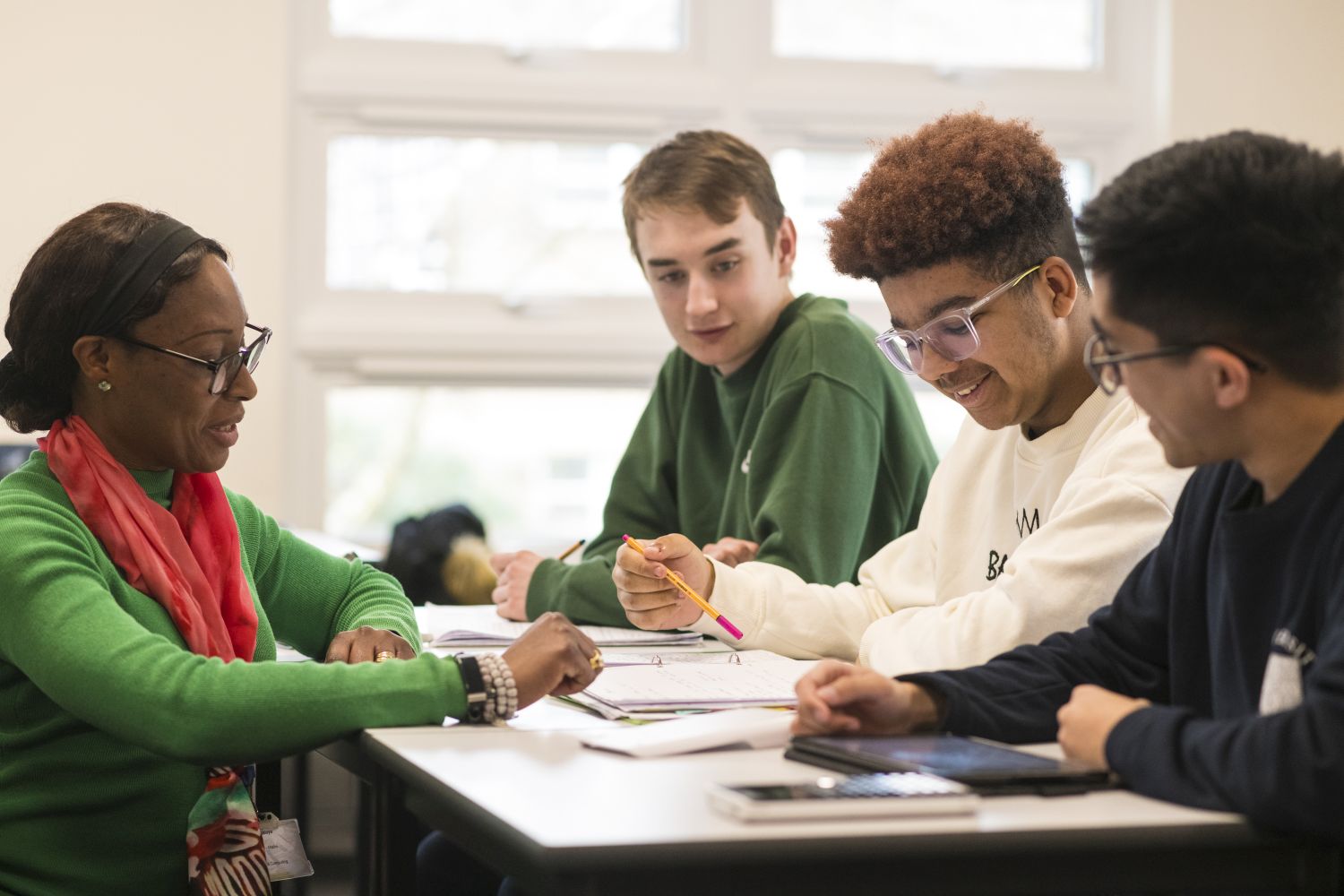 female teacher looking at maths textbook with 3 male students