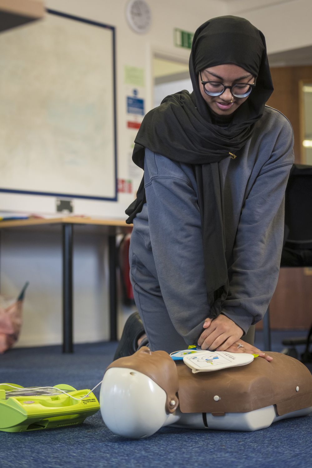 female student performing CPR on a human mannequin 